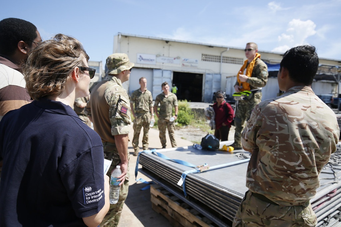 Humanitarian workers and military personnel in a planning session, possibly discussing the deployment of technological resources for an aid mission.