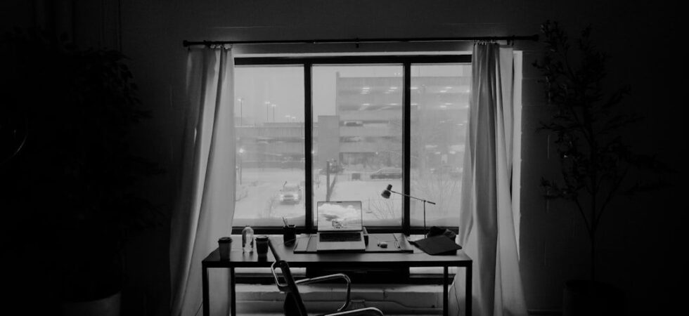 Minimalist home office with laptop, desk lamp, and snowy city view